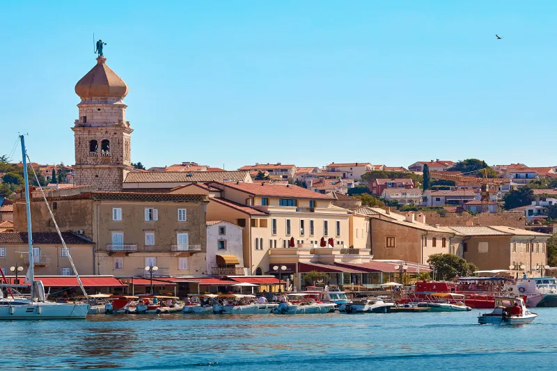 Apartamentos Krk: vista del casco antiguo y del puerto de la isla de Krk con barcos tradicionales y una iglesia al fondo