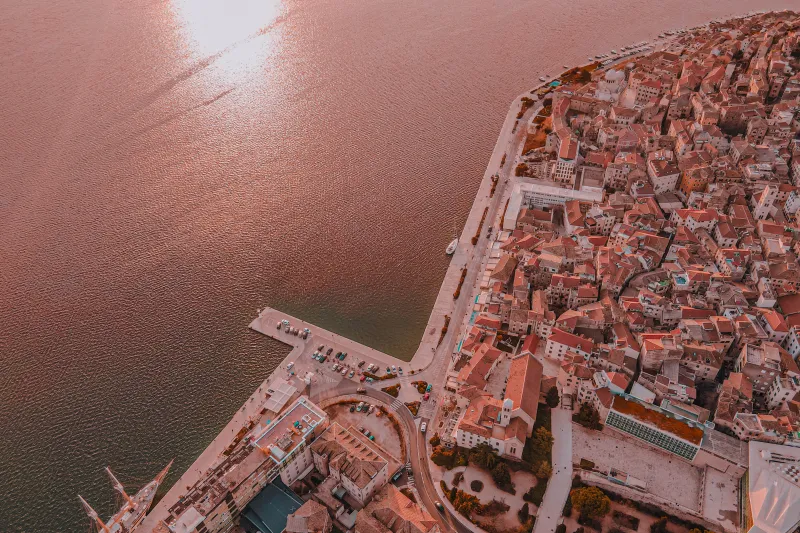 Apartamentos en Šibenik - vista aérea de la parte histórica de la ciudad junto al mar al atardecer.
